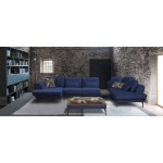 Μπλε γωνιακός καναπές “Roche” τοποθετημένος σε industrial boho loft: πέτρινοι τοίχοι, γκρι μοκέτα και ράφι βιβλιοθήκης. (Thumb 11)