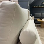 Κοντινό πλάνο στο εργονομικό κυλινδρικό μαξιλάρι και την πλάτη του εκρού καναπέ Flex στον εκθεσιακό χώρο. (Thumb 6)