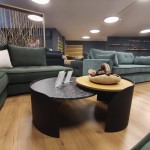 Πλάγια άποψη του εκθεσιακού coffee table Galaxias ανάμεσα σε μοντέρνους καναπέδες, προβάλλοντας το αρμονικό του σχήμα. (Thumb 2)