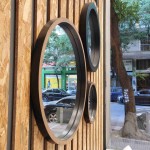 Πλαϊνή άποψη του σετ στρογγυλών καθρεφτών Room με βαθύ ξύλινο και μαύρο πλαίσιο, τοποθετημένων σε τοίχο με ξύλινες επενδύσεις. (Thumb 3)
